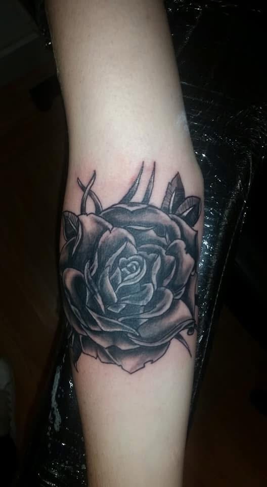 Black and grey rose with thorns and leaves arm tattoo