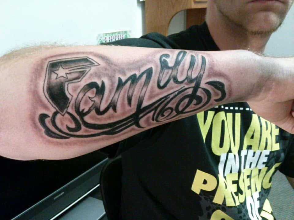 Family bold script lettering with star shield forearm tattoo