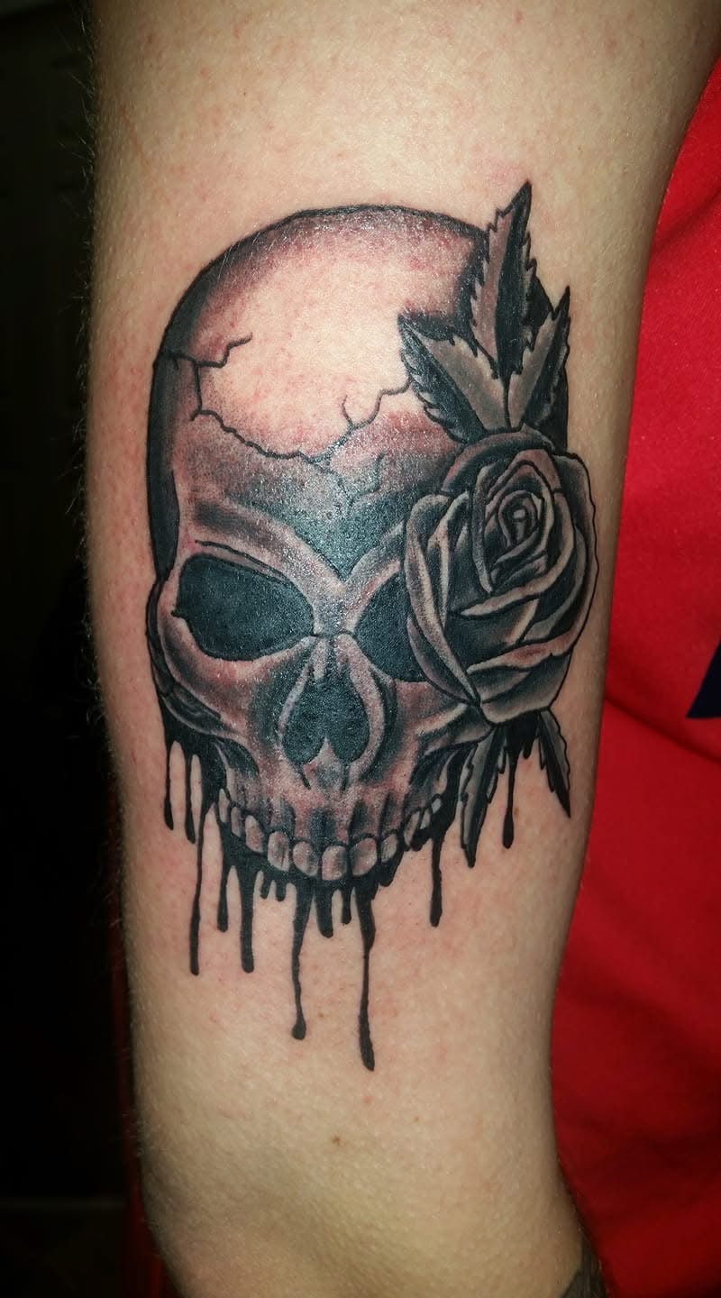 Dripping skull with rose and feather arrow forearm tattoo