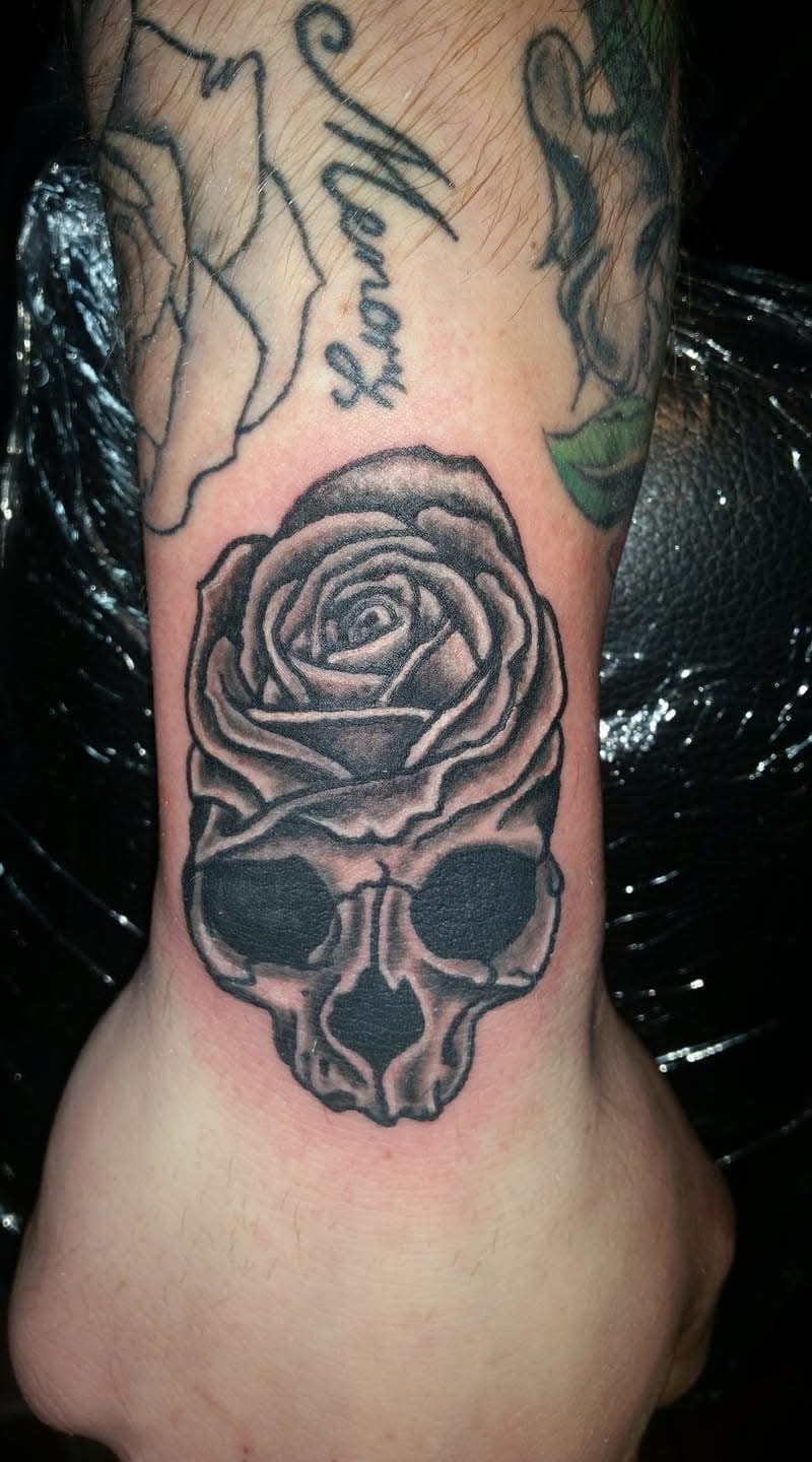 Rose merging into skull face wrist tattoo
