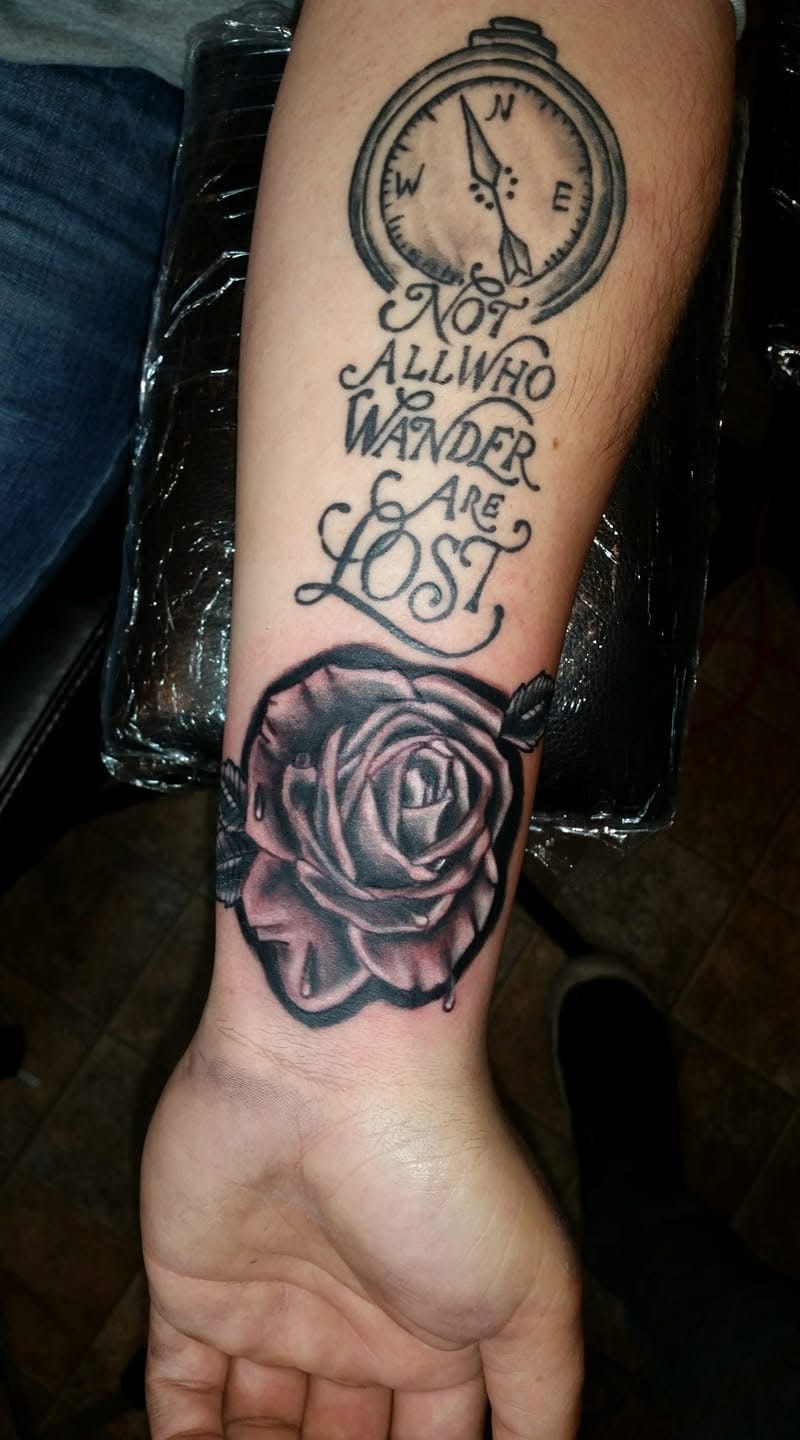 Compass with Not All Who Wander Are Lost quote and rose forearm tattoo