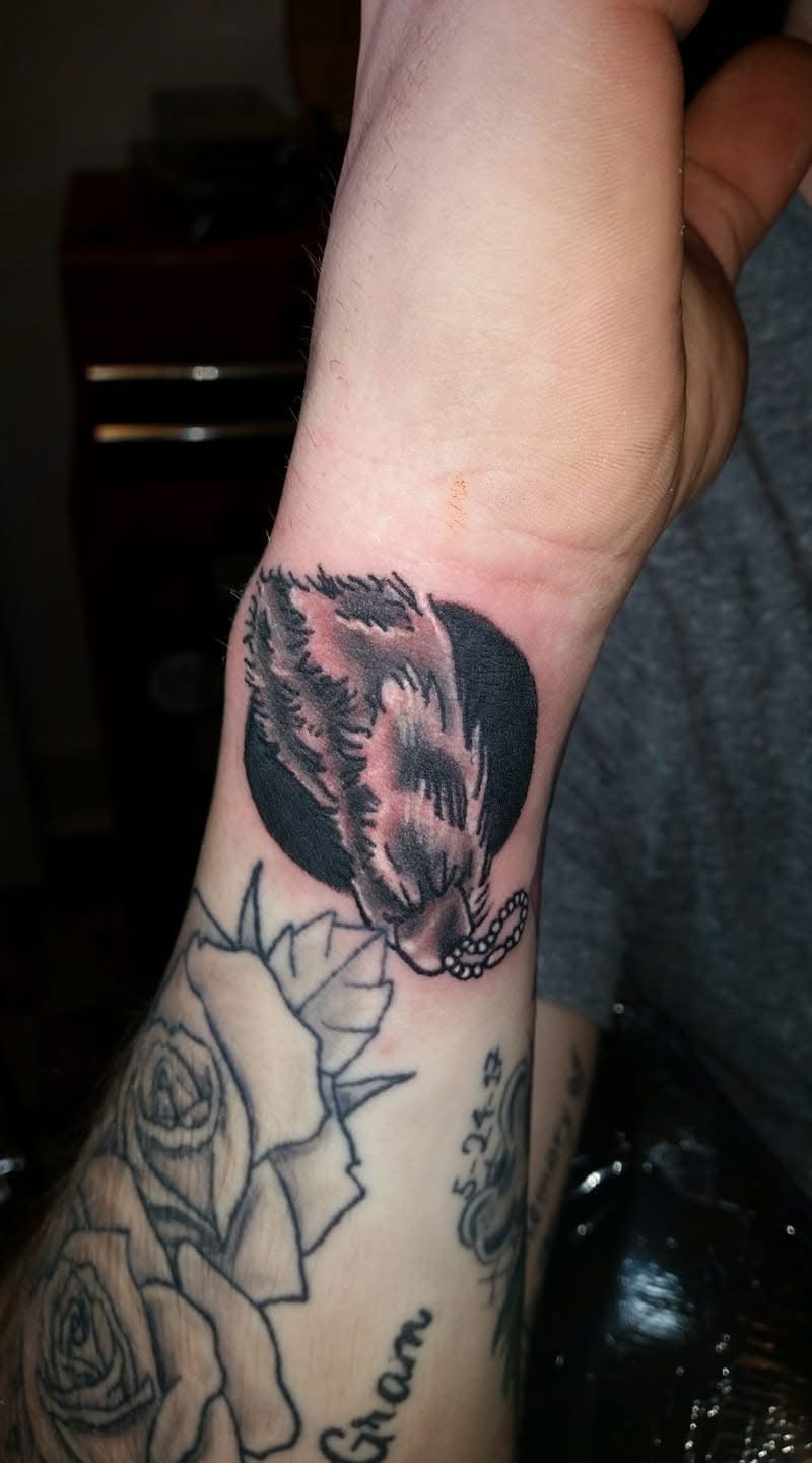 Wolf howling at black moon circle wrist tattoo