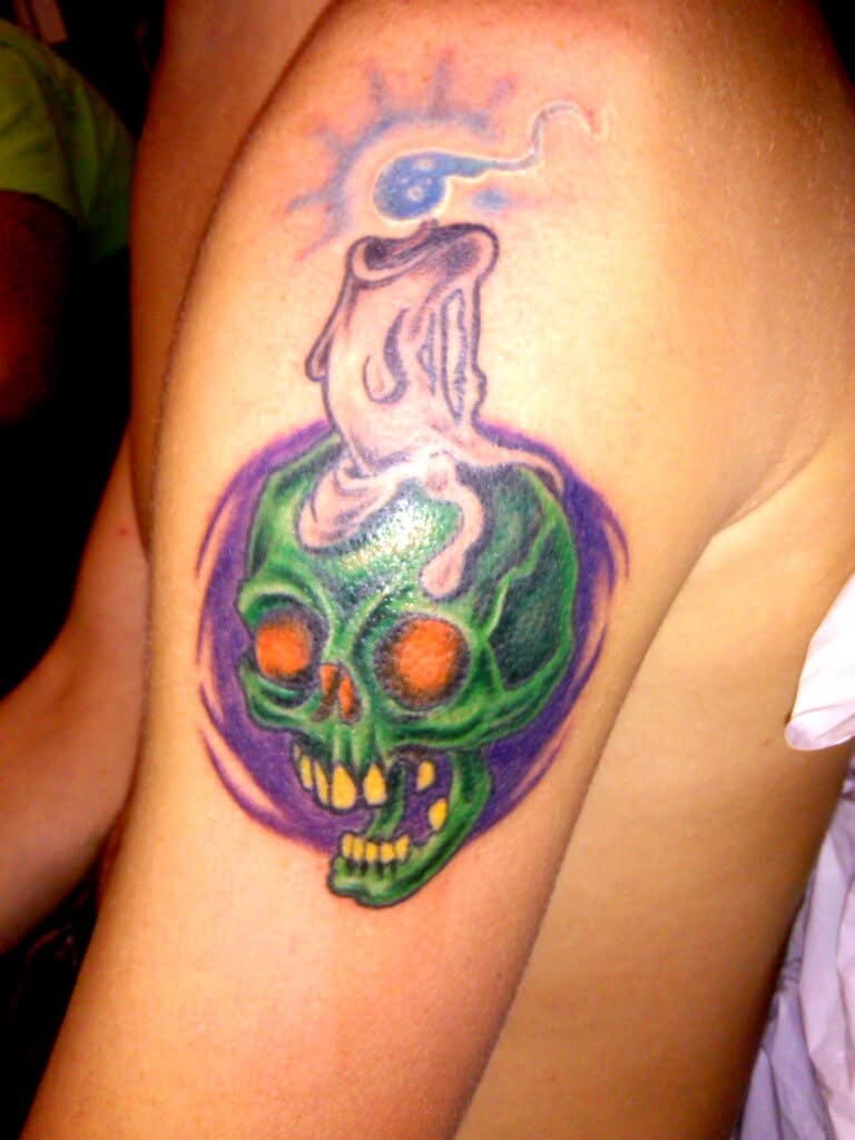 Green ghost skull with orange eyes colorful arm tattoo