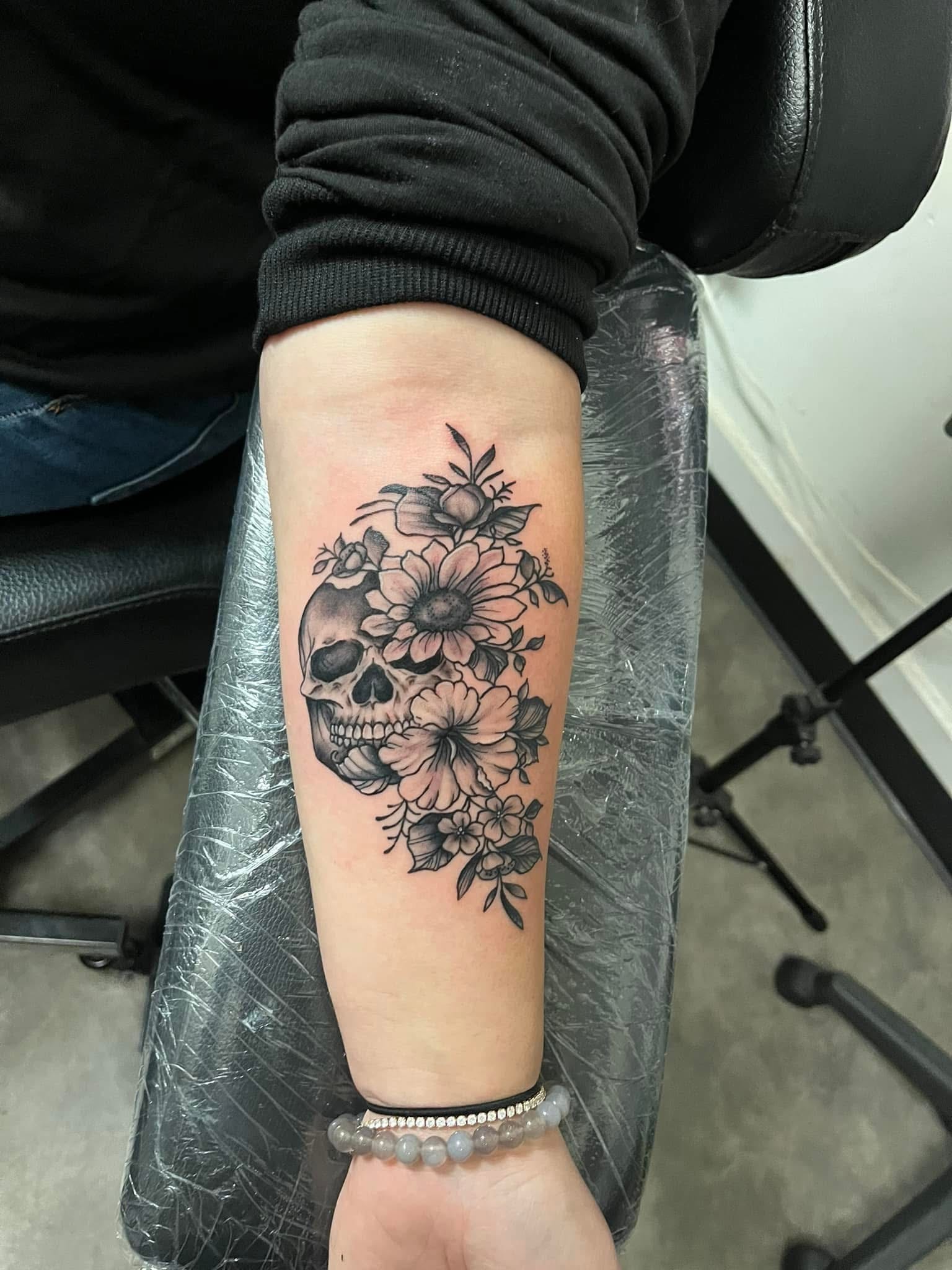 Skull with sunflowers and wildflowers forearm tattoo