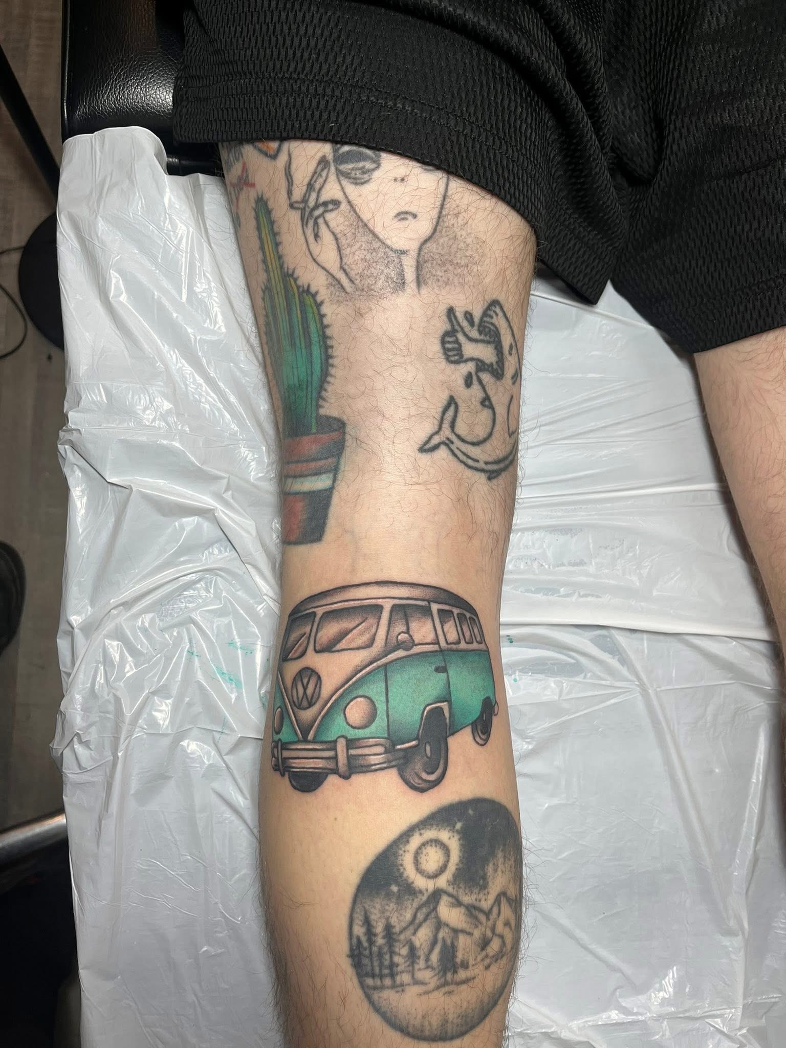 Teal VW bus leg tattoo with mountain moon scene below