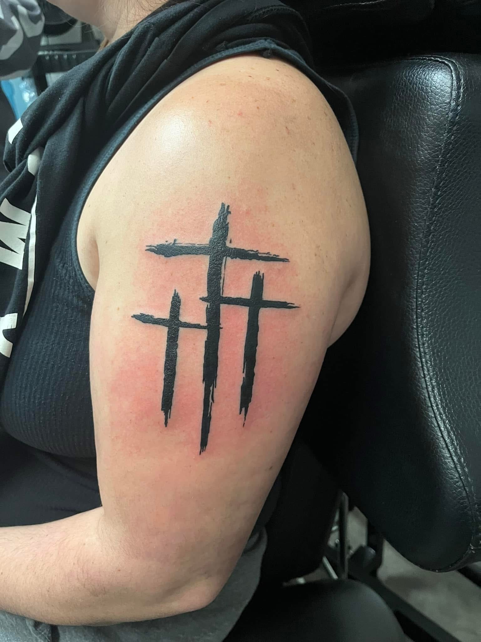 Three bold brushstroke crosses upper arm tattoo