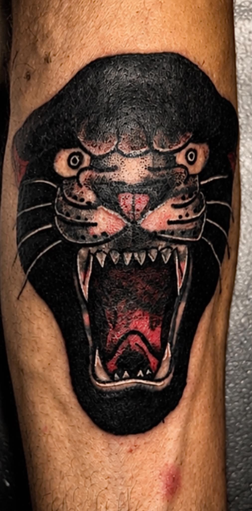 Black panther head with open mouth arm tattoo